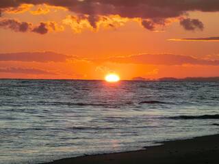沈みゆく夕日と穏やかに打ち寄せる波