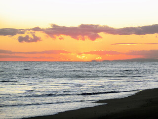 オレンジ色に染まる夕焼けの空模様と穏やかな波打ち際