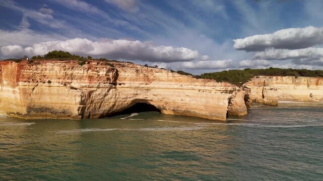 Aerial Approach Over the Atlantic Ocean Towards the Iconic Benagil Sea Cave and Rugged Limestone Coastline of the Algarve in Portugal