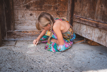 M&auml;dchen malt mit Malkreide am Boden