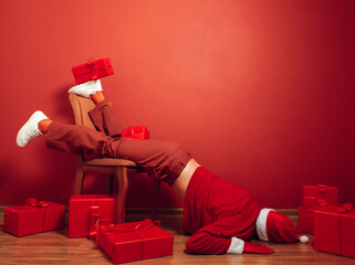 Santa in red room overwhelmed by Christmas gifts and holiday burnout