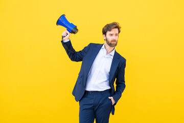 Businessman with megaphone gestures on yellow background