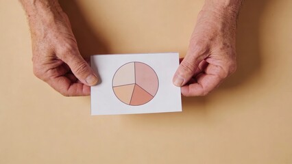 Hands holding paper with pie chart on beige background ,Active aging Finance concept.