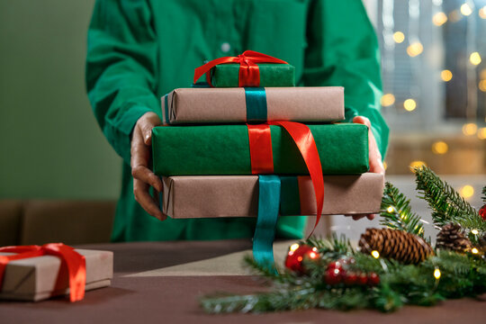 Woman holding wrapped Christmas gifts with festive decorations indoors