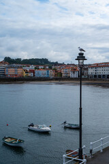 A few boats float on the water in Luanco, a village in Asturias. The sky is cloudy and the water is calm.