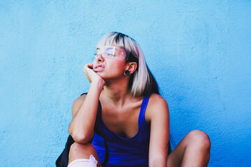 Alternative student in blue with tech glasses sitting pensively