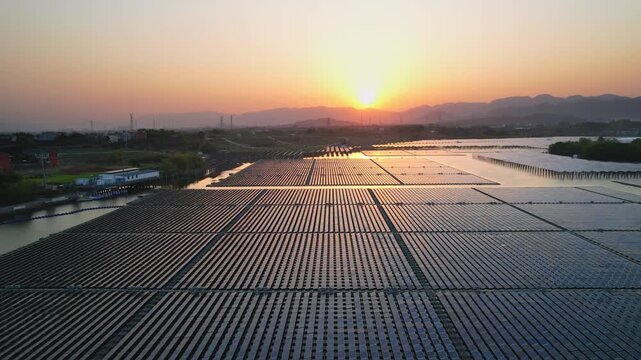 Large photovoltaic power station array at sunset with distant mountains and river