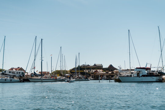 Scenic view of Varberg harbor with sailboats and the historic Varberg Fortress under a clear blue sky, Sweden