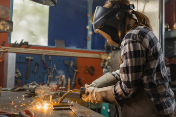 A female welder is working in a workshop, showcasing her skills in a technical role. This highlights womens contributions in industry.