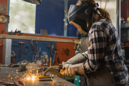 A female welder is working in a workshop, showcasing her skills in a technical role. This highlights womens contributions in industry.