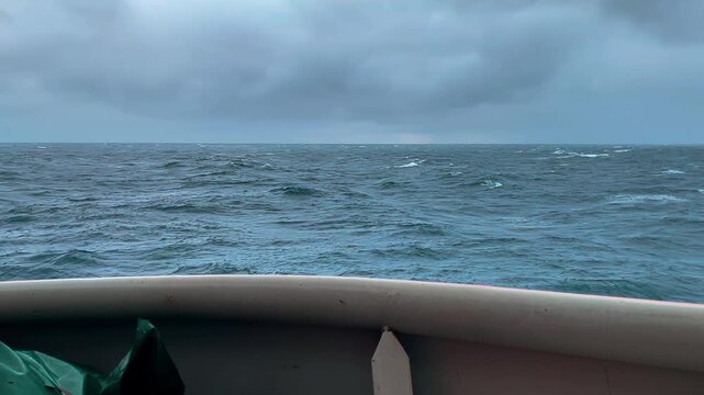 Peaceful maritime scene with lone skipper watching gentle undulating waters beneath soft clouds
