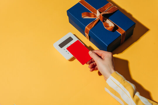 Contactless payment by card and blue gift box on yellow background