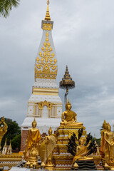 Fototapeta premium Phra That Phanom, iconic Buddhist stupa with golden carvings and white architecture, rising against a bright blue sky. Sacred Thai temple landmark, rich cultural heritage and spiritual atmosphere