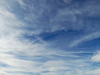 Wispy white cirrus clouds on a bright blue sky background
