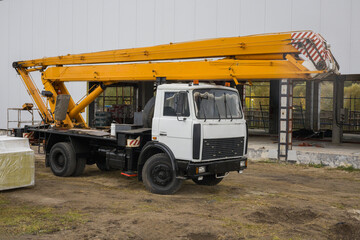 A large construction vehicle is parked at a construction site. The boom arm is extended, showing the equipment's capability to lift materials © Anoo