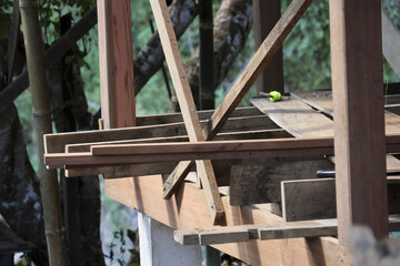 Unfinished wooden house structure with beams and planks under construction showing peaceful rural atmosphere outdoors surrounded by green nature