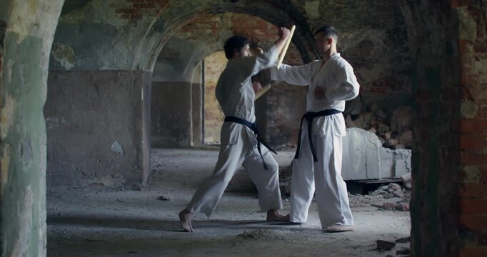 Two karate practitioners simulate a fight in which one of them uses nunchucks.