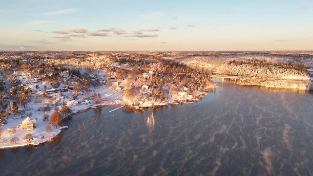 Beautiful sunrise over the archipelago of Stockholm, Sweden, after a snowstorm, with houses and docks on the hill