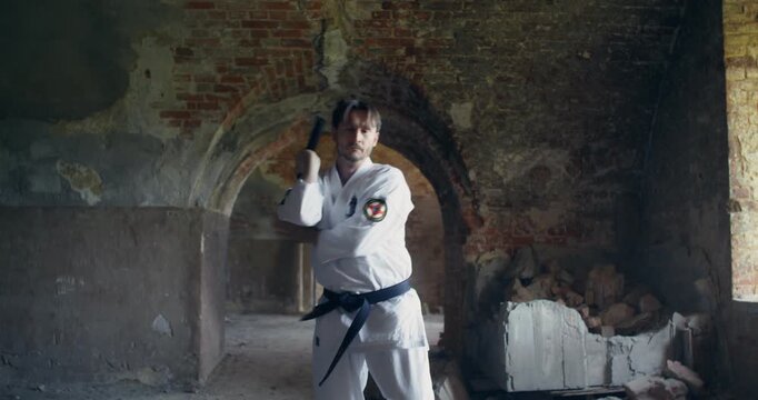 A male karateka uses nunchucks in combat to attack. A young karateka demonstrates various types of punches and kicks used in karate.
