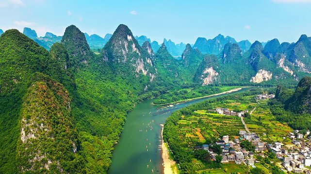 Aerial shot of spectacular karst mountain peaks and winding river with rural village scenery in Guilin, China.