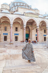 Woman in a traditional oriental robe in the courtyard of the Suleymaniye Mosque.
