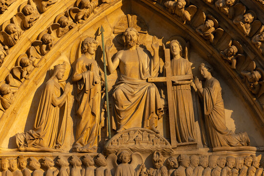 Paris, France - Central portal, depicting the Last Judgment on the west facade of Notre Dame Cathedral, restored after the fire, looks beautiful in the glow of the setting sun.