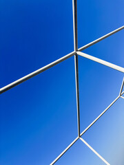 Abstract intersection of white metal pipes against blue sky