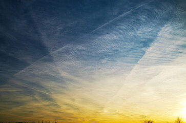 Vast sky with wispy clouds and contrails at sunset, a beautiful natural phenomenon