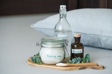 Baking soda, vinegar, lemon and borax, salt are placed on a wooden tray. The scene shows a tidy indoor space with natural light. Sustainable bedding care concept