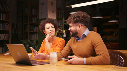 Successful colleagues sitting on table in modern office using laptop, working, planning project