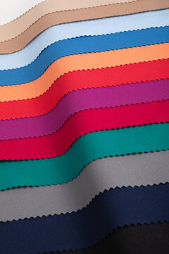 Studio close-up of colorful fabric swatches arranged in elegant folds, showcasing vibrant and pastel tones with pinked edges. Fine textures and controlled lighting highlight high-quality textiles for 