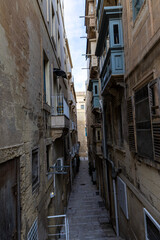 Fototapeta premium Narrow old streets with windowed buildings and colorful balconies on the streets of Valletta, Malta.