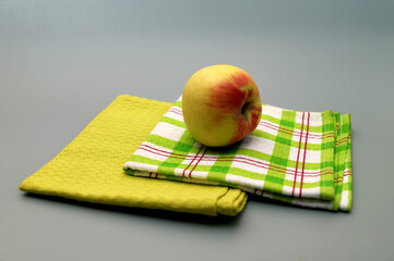 A ripe yellow apple lies on green napkins.