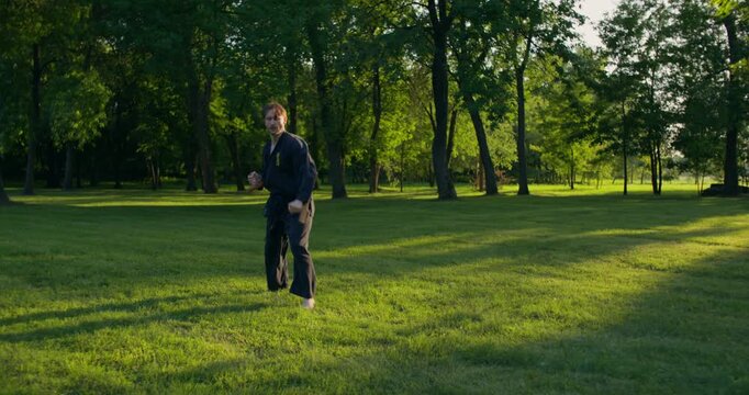 Man using tonfu during karate training. A male karateka trains on the grass with nunchaku and tonfa.