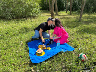 Romantic couple kissing during a summer picnic in a park.