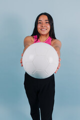 portrait of young latin teenager girl holding a soccer ball with copy space on blue background in Mexico Latin America, Hispanic and brunette woman