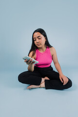 young latin teenager girl holding and using mobile phone with copy space on blue background in Mexico Latin America, Hispanic brunette young woman