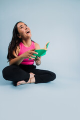 young latina teenager girl reading a book with copy space on blue background in Mexico Latin America, Hispanic brunette young woman