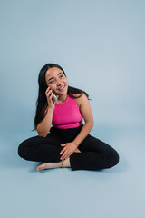young latin teenager girl holding and using mobile phone with copy space on blue background in Mexico Latin America, Hispanic brunette young woman