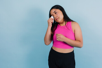 portrait of young latina teenager girl crying or with sad face with copy space on blue background in Mexico Latin America, Hispanic and brunette woman