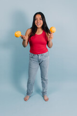 portrait of young latin teenager girl dancing and holding maracas with copy space on blue background in Mexico Latin America, Hispanic brunette woman