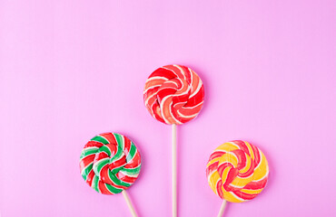 Three striped lollipops on pink background. Flat lay. View from above, copy space