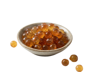 A rustic ceramic bowl filled with glossy, amber-colored boba pearls, with a few spilled beside it.