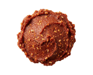 A round dollop of rich, reddish-brown paste swirled and textured with small sesame seeds, seen from above.