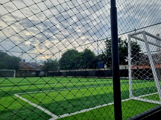 Futsal court enclosed by wire fence, outdoor sports field with artificial turf, suitable for...