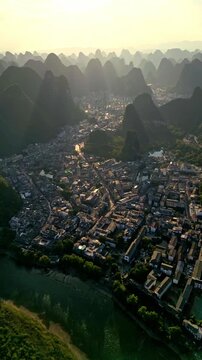 Aerial view of the city nestled among the dramatic karst mountains, with a river reflecting the sunlight, Guilin, Guangxi, China.