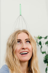 Young beautiful happy woman using hair scalp massager. Playful woman enjoying wire head massager for relaxation