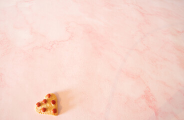 Valentines  single  heart shaped cookie   on a  pink back ground  copy  space 