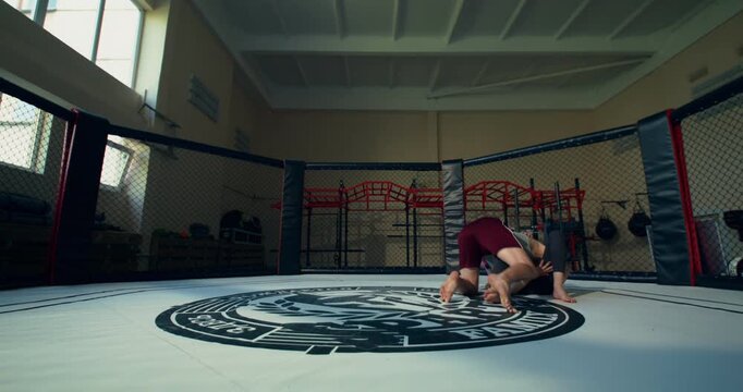 A female mixed martial artist works with her coach on her opponent's takedown technique in the ring.