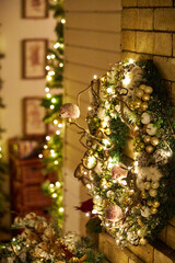 Cozy Christmas interior with festive garland lights and beautifully decorated holiday wreath on a brick fireplace. Warm home atmosphere, holiday spirit, winter celebration and family comfort